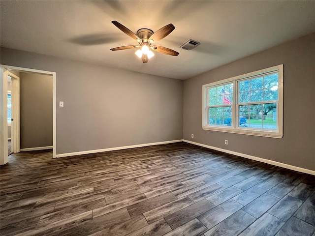 empty room with visible vents, baseboards, ceiling fan, and dark wood-style flooring