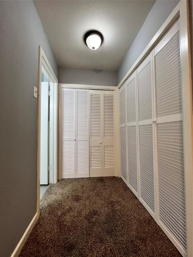 hall with a textured ceiling and carpet floors