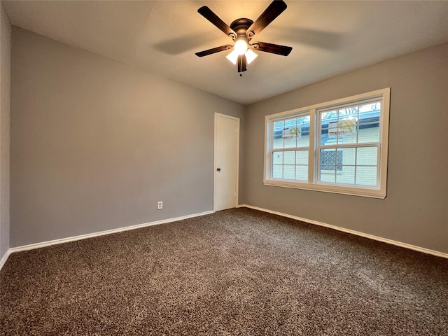 empty room with ceiling fan, baseboards, and dark colored carpet