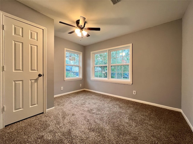 carpeted empty room featuring visible vents, baseboards, and ceiling fan