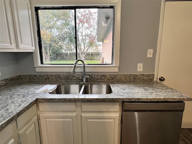 kitchen with light stone countertops, dishwasher, white cabinetry, and a sink