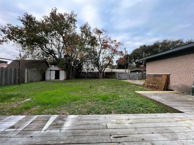 view of yard with a deck, an outdoor structure, a storage unit, and a fenced backyard