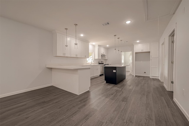 kitchen with kitchen peninsula, a kitchen island, electric stove, white cabinetry, and hanging light fixtures