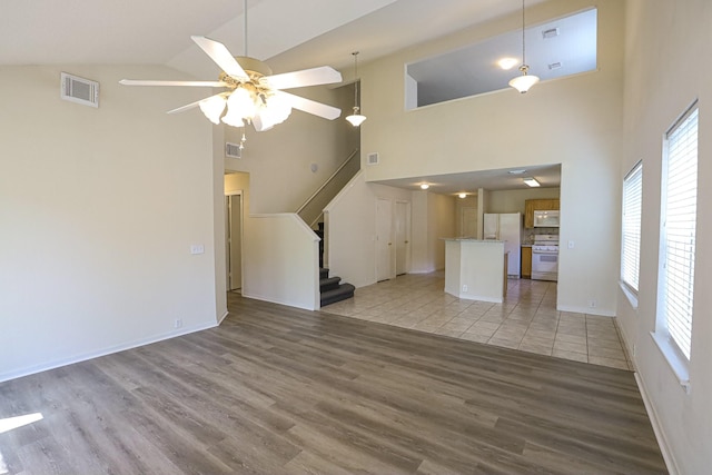 unfurnished living room with high vaulted ceiling, light hardwood / wood-style flooring, and ceiling fan