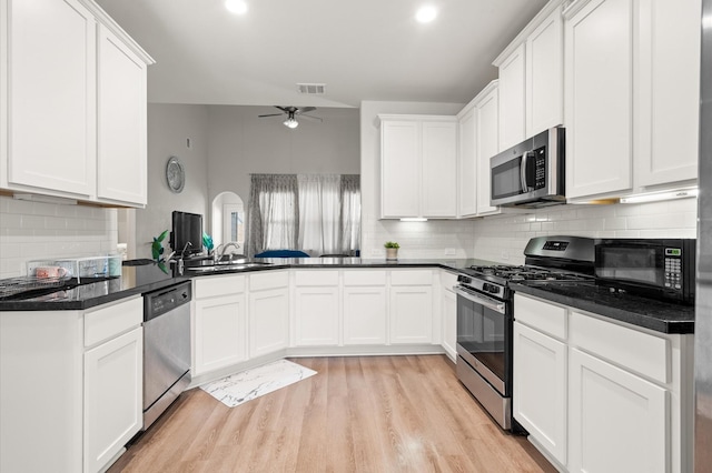 kitchen with appliances with stainless steel finishes, white cabinetry, sink, kitchen peninsula, and ceiling fan