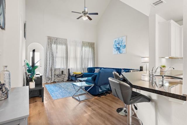 office featuring high vaulted ceiling, sink, ceiling fan, and light wood-type flooring