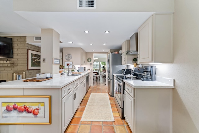 kitchen with white cabinets, wall chimney range hood, sink, kitchen peninsula, and stainless steel appliances