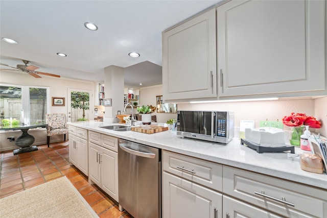 kitchen with sink, light tile patterned floors, appliances with stainless steel finishes, light stone counters, and white cabinetry