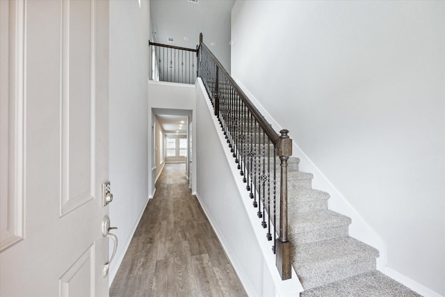 stairs featuring hardwood / wood-style flooring and a towering ceiling