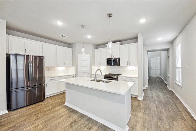 kitchen featuring appliances with stainless steel finishes, white cabinetry, and hanging light fixtures