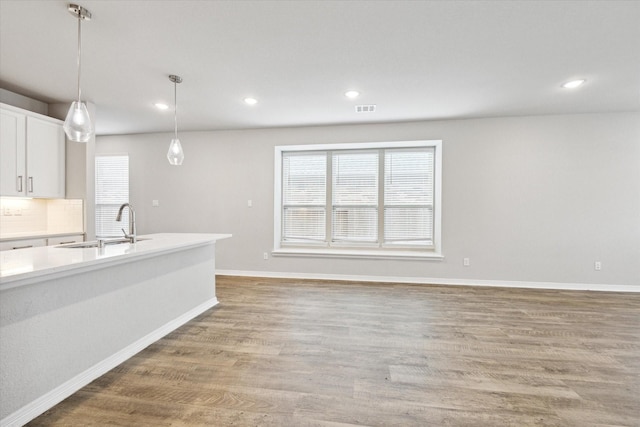 kitchen with white cabinetry, sink, tasteful backsplash, pendant lighting, and light hardwood / wood-style floors