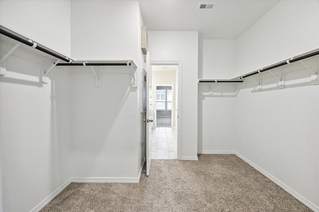 spacious closet featuring light colored carpet