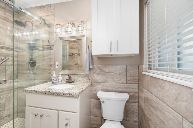 bathroom with tile walls, vanity, an enclosed shower, and toilet