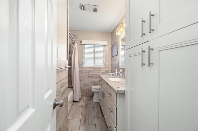 full bathroom featuring shower / tub combo with curtain, vanity, tile walls, and toilet