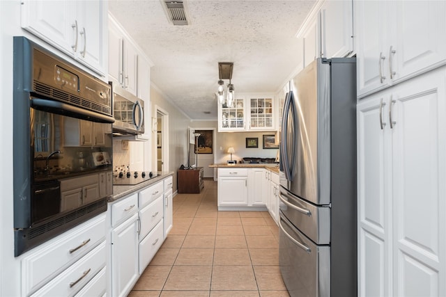 kitchen featuring a textured ceiling, black appliances, light tile patterned floors, white cabinetry, and hanging light fixtures