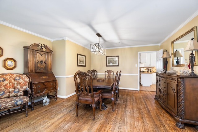 dining space with crown molding, wood-type flooring, and a notable chandelier