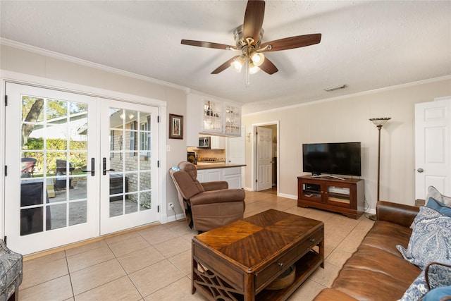 living room with french doors, light tile patterned floors, ceiling fan, and ornamental molding