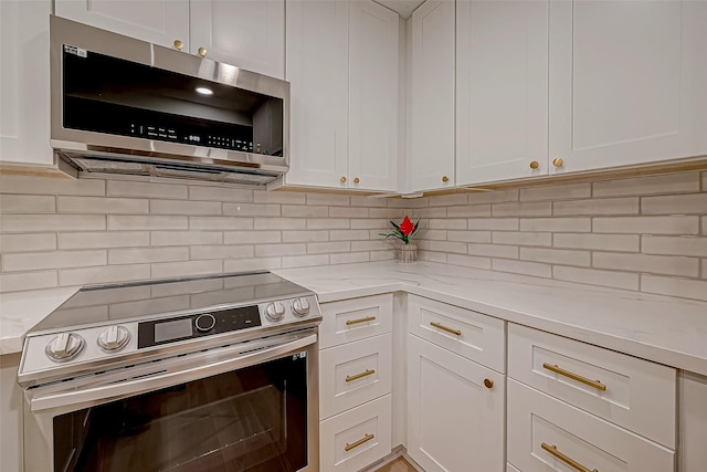 kitchen featuring stainless steel appliances, white cabinetry, and light stone counters