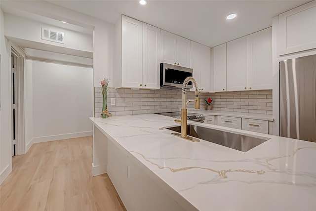 kitchen featuring white cabinetry, light stone counters, and appliances with stainless steel finishes