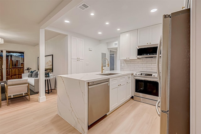 kitchen with sink, tasteful backsplash, light stone counters, white cabinetry, and stainless steel appliances