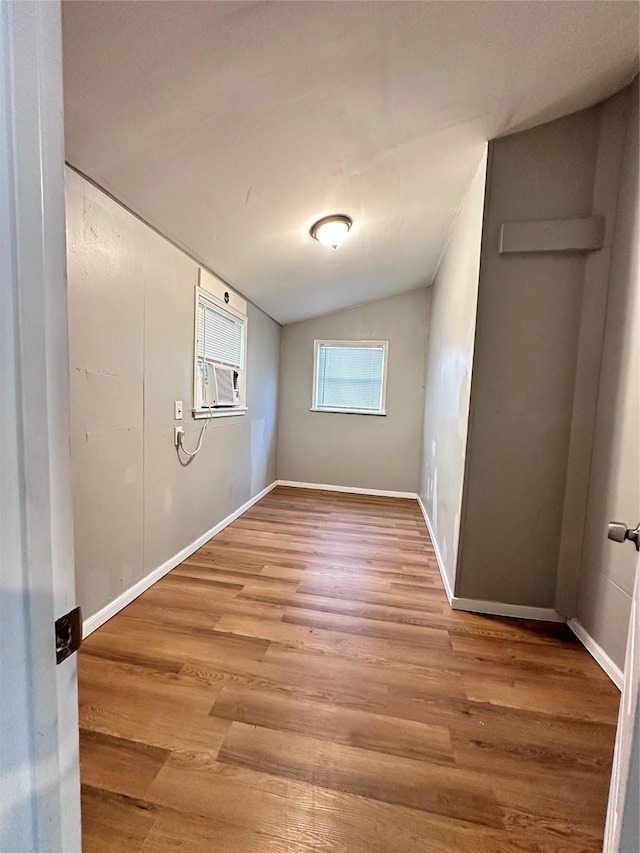 unfurnished room featuring wood-type flooring, cooling unit, and lofted ceiling