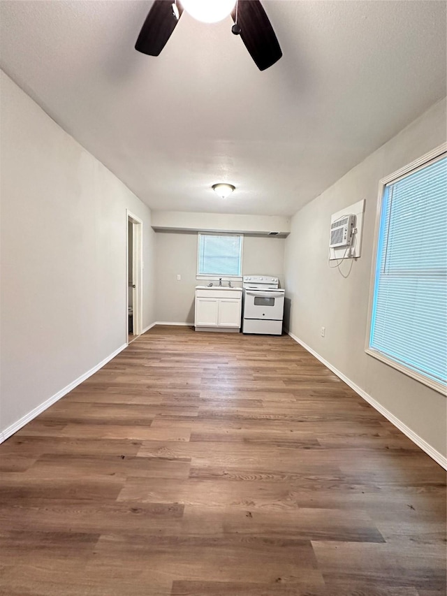 interior space featuring an AC wall unit, ceiling fan, and hardwood / wood-style floors