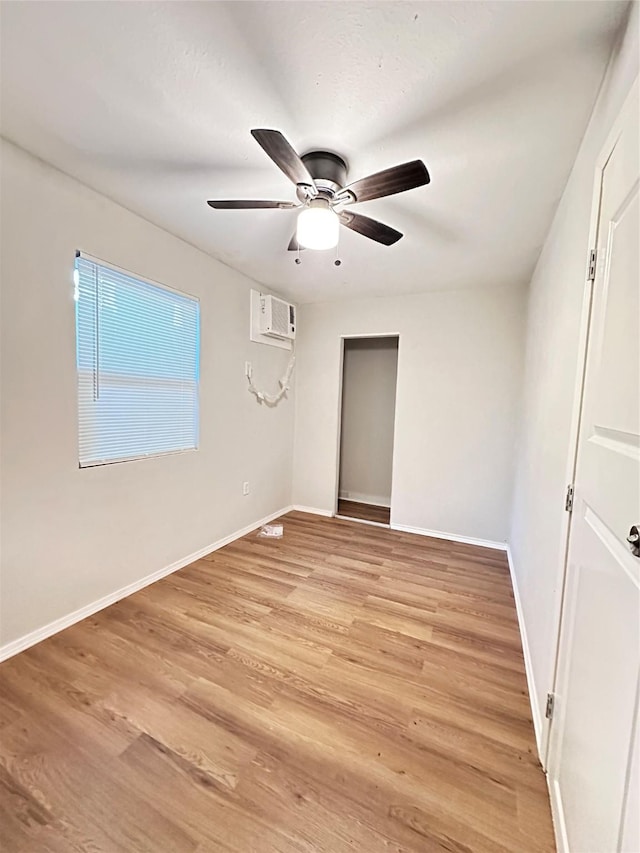 unfurnished bedroom featuring ceiling fan, light hardwood / wood-style floors, and a wall mounted AC