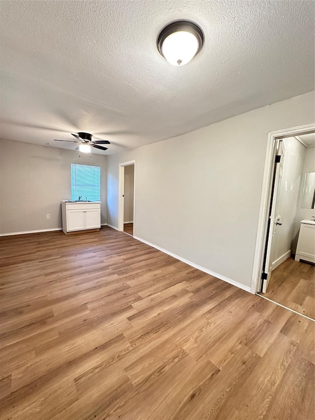 unfurnished bedroom featuring ceiling fan, light wood-type flooring, and a textured ceiling