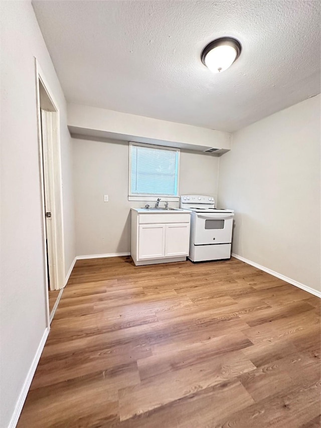 kitchen featuring a textured ceiling, light hardwood / wood-style flooring, white cabinetry, and electric stove