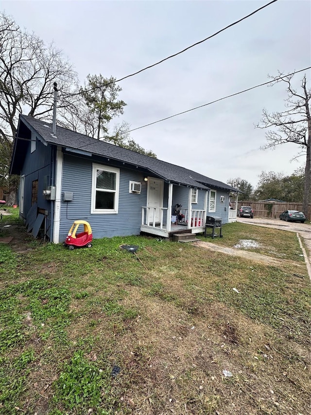 view of front facade featuring a wall unit AC and a front lawn