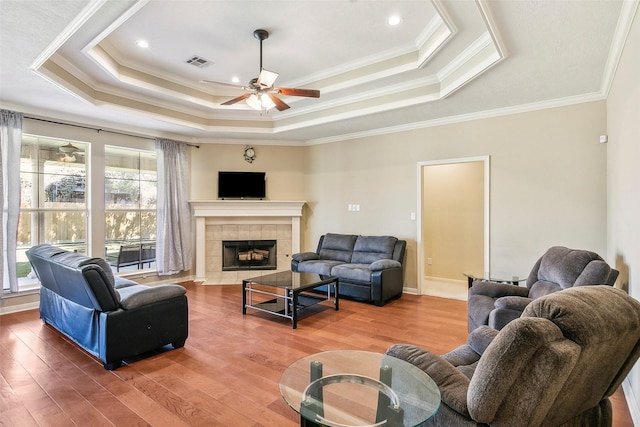 living room featuring a tray ceiling, plenty of natural light, and ornamental molding