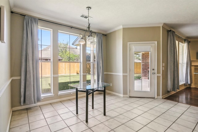 doorway with a textured ceiling, an inviting chandelier, crown molding, and light tile patterned flooring