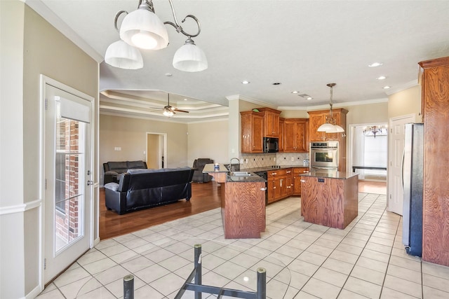 kitchen with kitchen peninsula, crown molding, pendant lighting, a kitchen island, and stainless steel refrigerator