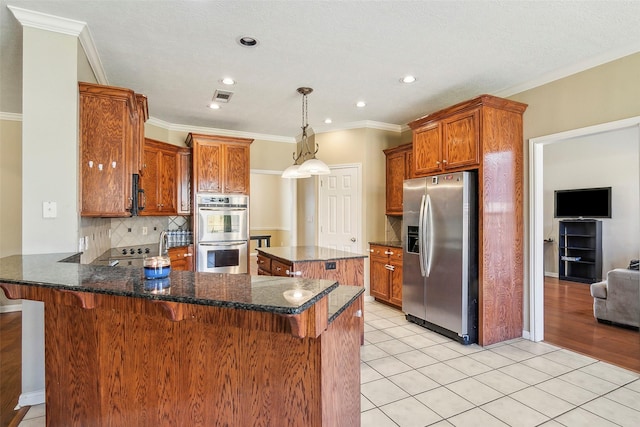 kitchen featuring stainless steel appliances, kitchen peninsula, decorative backsplash, a breakfast bar, and light tile patterned flooring