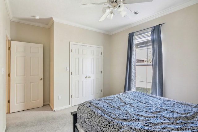 bedroom with crown molding, ceiling fan, a closet, and light colored carpet