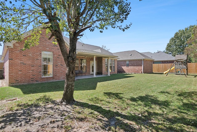 rear view of property featuring a playground, a patio area, and a lawn