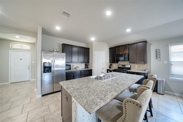 kitchen with a kitchen bar, tasteful backsplash, stainless steel appliances, sink, and a center island with sink