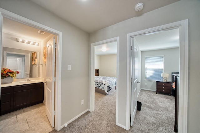 hall featuring light colored carpet and sink