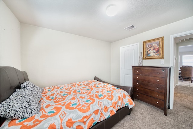 bedroom with light colored carpet and a textured ceiling