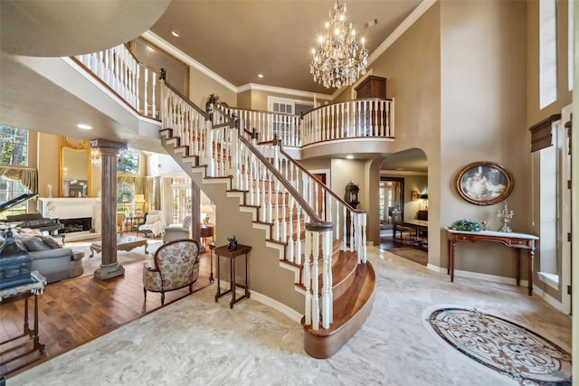 entryway featuring a high ceiling, an inviting chandelier, crown molding, and wood-type flooring