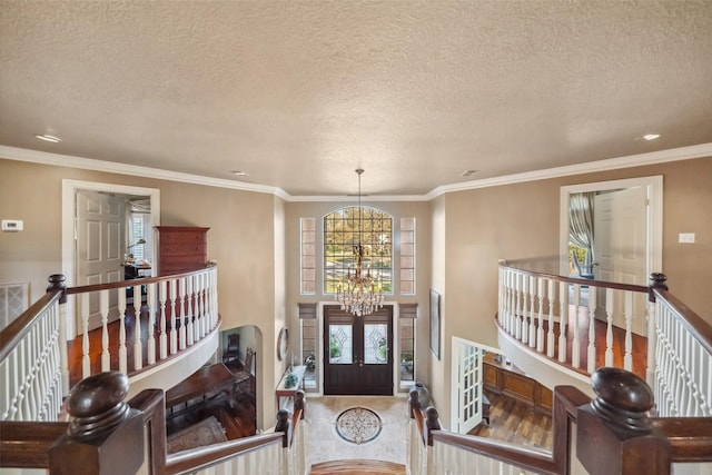 entryway featuring french doors, a textured ceiling, an inviting chandelier, and ornamental molding