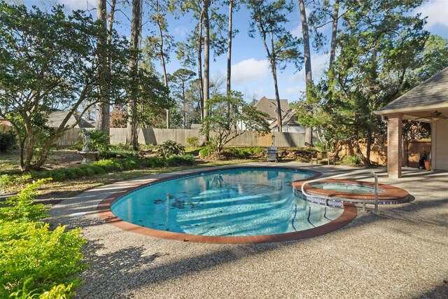 view of swimming pool with a patio, fence, and a pool with connected hot tub