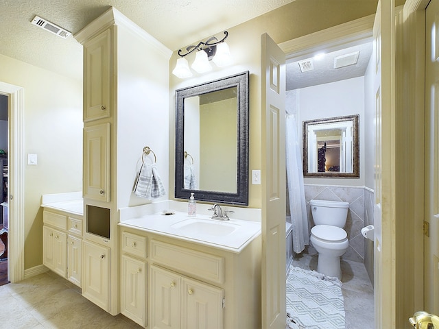 bathroom with vanity, tile patterned flooring, toilet, tile walls, and a textured ceiling