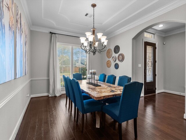 dining room with a tray ceiling, crown molding, dark wood-type flooring, and a notable chandelier