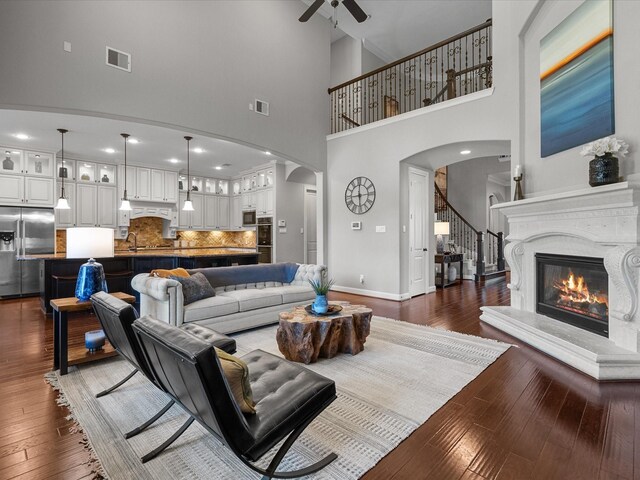 living room with a high ceiling, dark hardwood / wood-style flooring, ceiling fan, and sink