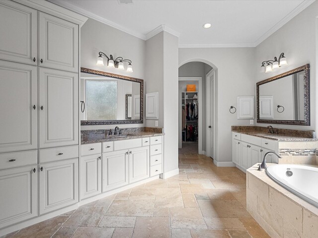 bathroom with vanity, a relaxing tiled tub, and crown molding