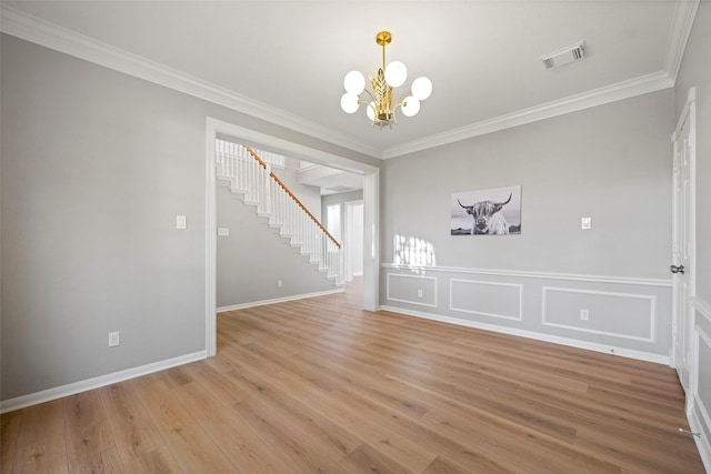 empty room with crown molding, light wood-type flooring, and a notable chandelier