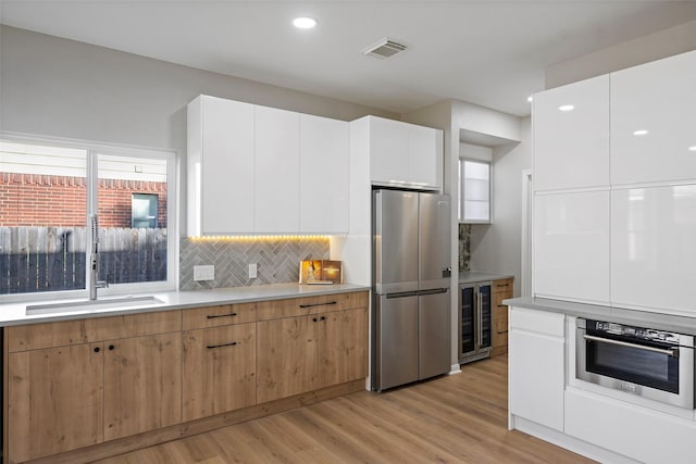 kitchen with white cabinetry, sink, tasteful backsplash, wine cooler, and appliances with stainless steel finishes