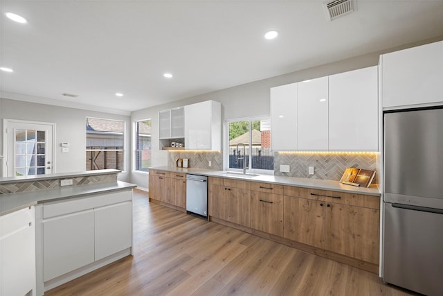 kitchen featuring tasteful backsplash, stainless steel appliances, sink, white cabinets, and light hardwood / wood-style floors