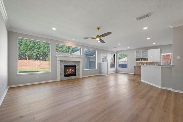 unfurnished living room featuring ceiling fan, light hardwood / wood-style floors, crown molding, and a high end fireplace